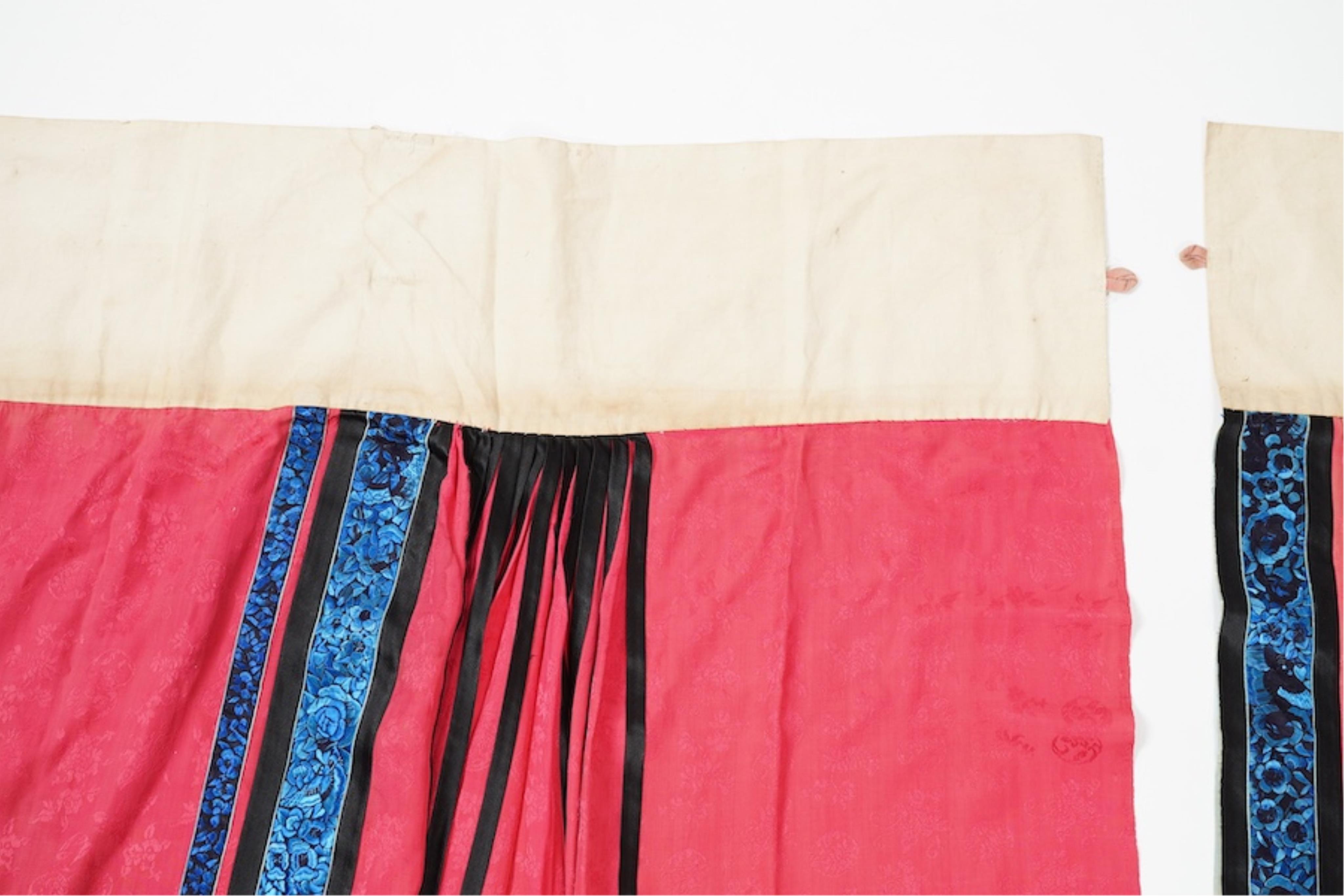 Two late 19th early 20th century Chinese wedding skirts. Made with pink silk damask, embroidered with large decorative silk floral and butterfly front panels bordered by blue embroidered black silk borders between pleats